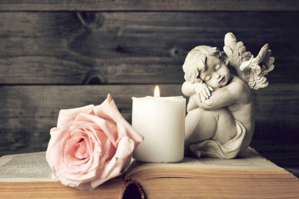 angel-candle-and-pink-rose-on-wooden-background